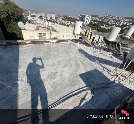 גג שטוח שעבר הלבנה ואיטום עם דודי שמש ברקע